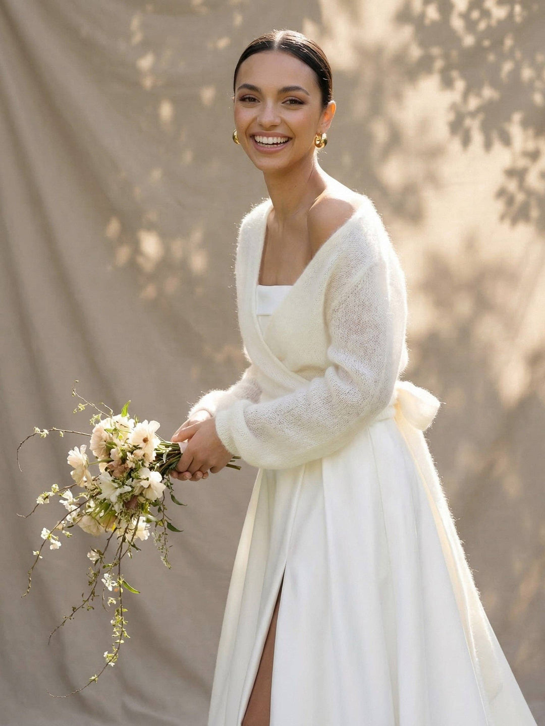 Cache-cœur de mariée en mohair ivoire porté avec un bouquet