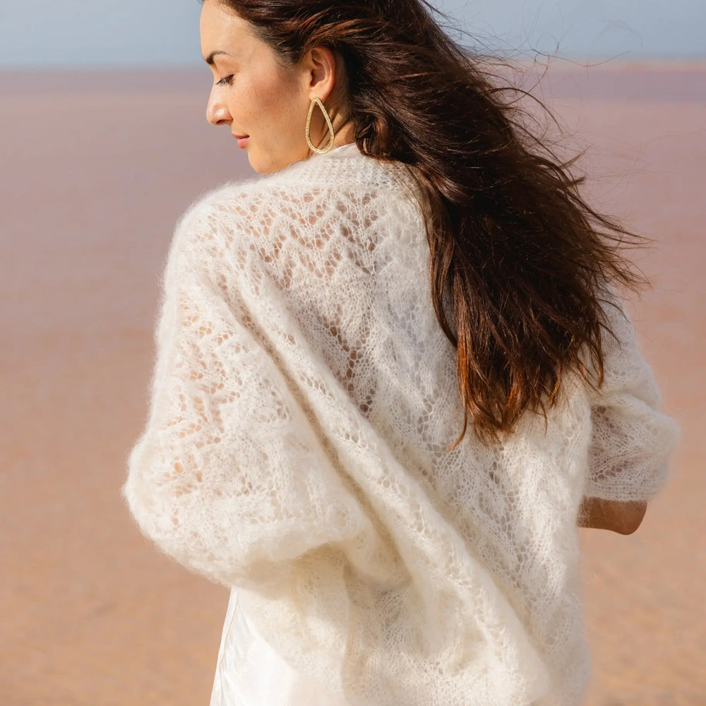 GILET MARIÉE EN MOHAIR & SOIE - TRICOTÉ MAIN BOHÈME CHIC - ANNABELLE mariage portée par femme brune vue de dos sur une plage - Adepte en collaboration avec Mas accessoires