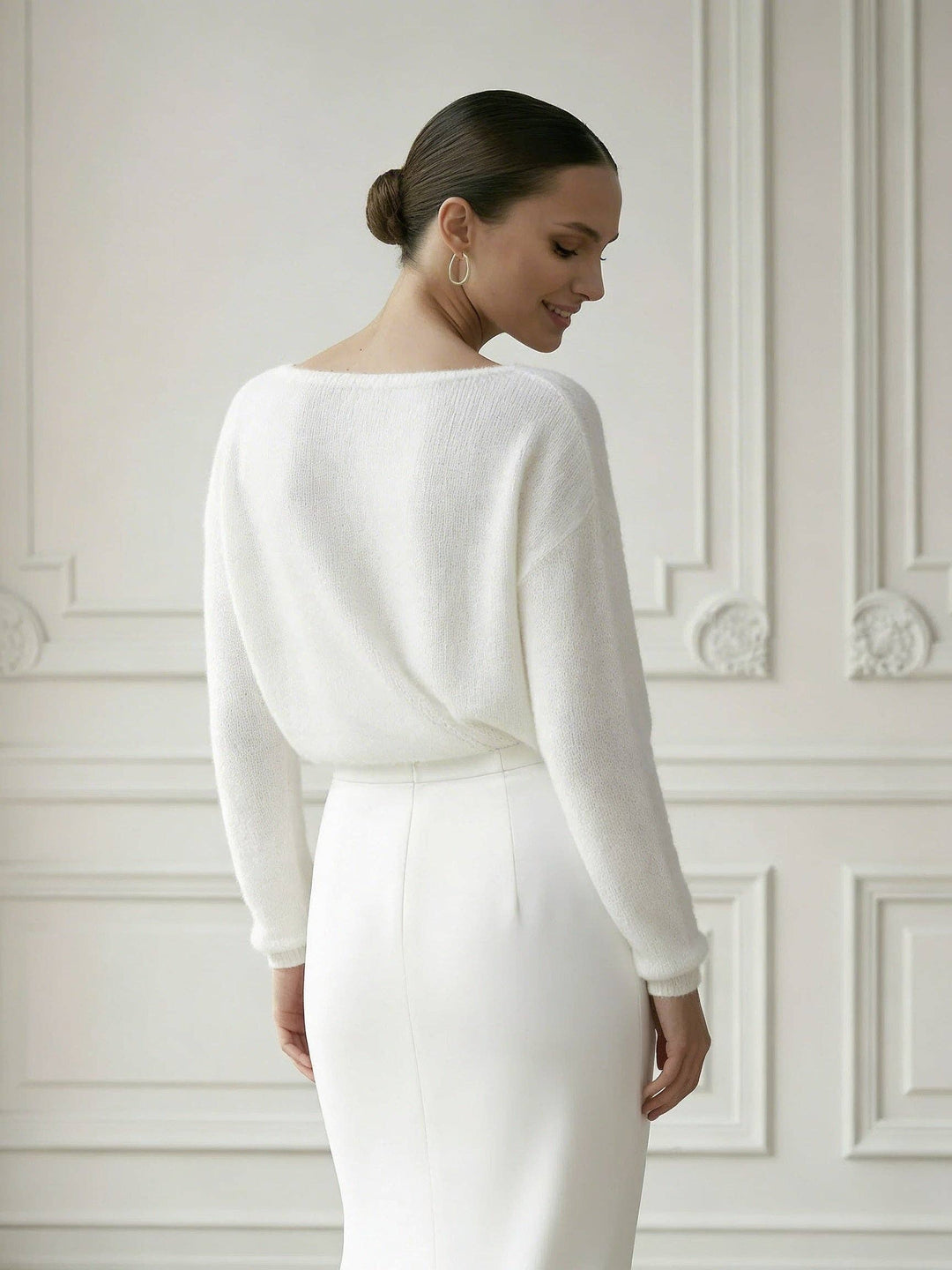 Mariée de dos en pull ivoire à longues manches, robe fourreau