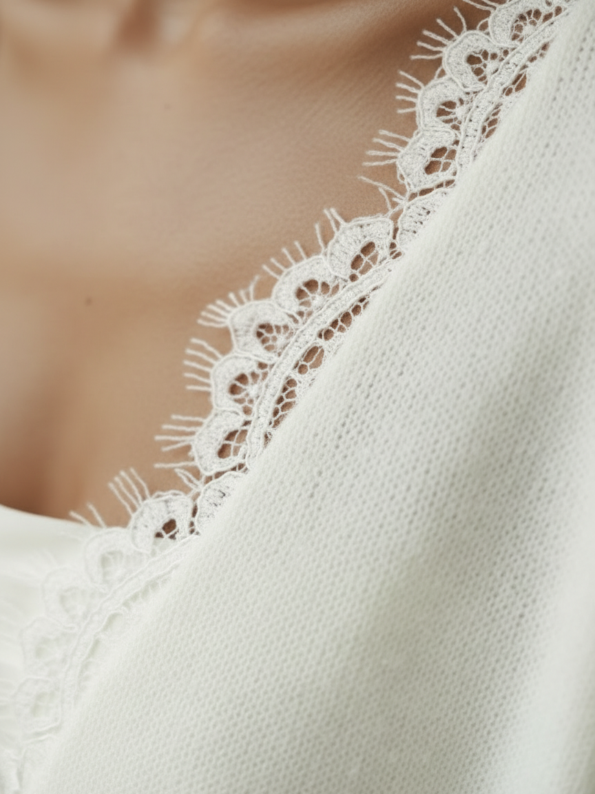 Gros plan sur la dentelle fine du col V du pull de mariée