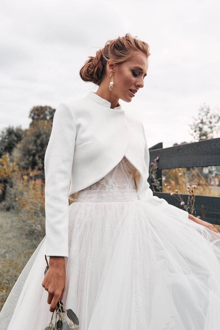 Veste de mariée courte ivoire portée avec un bouquet d'eucalyptus