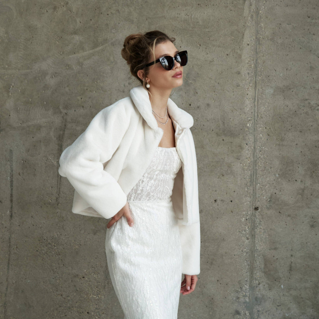Manteau de mariée court en fausse fourrure ivoire, col châle, porté sur une robe bustier