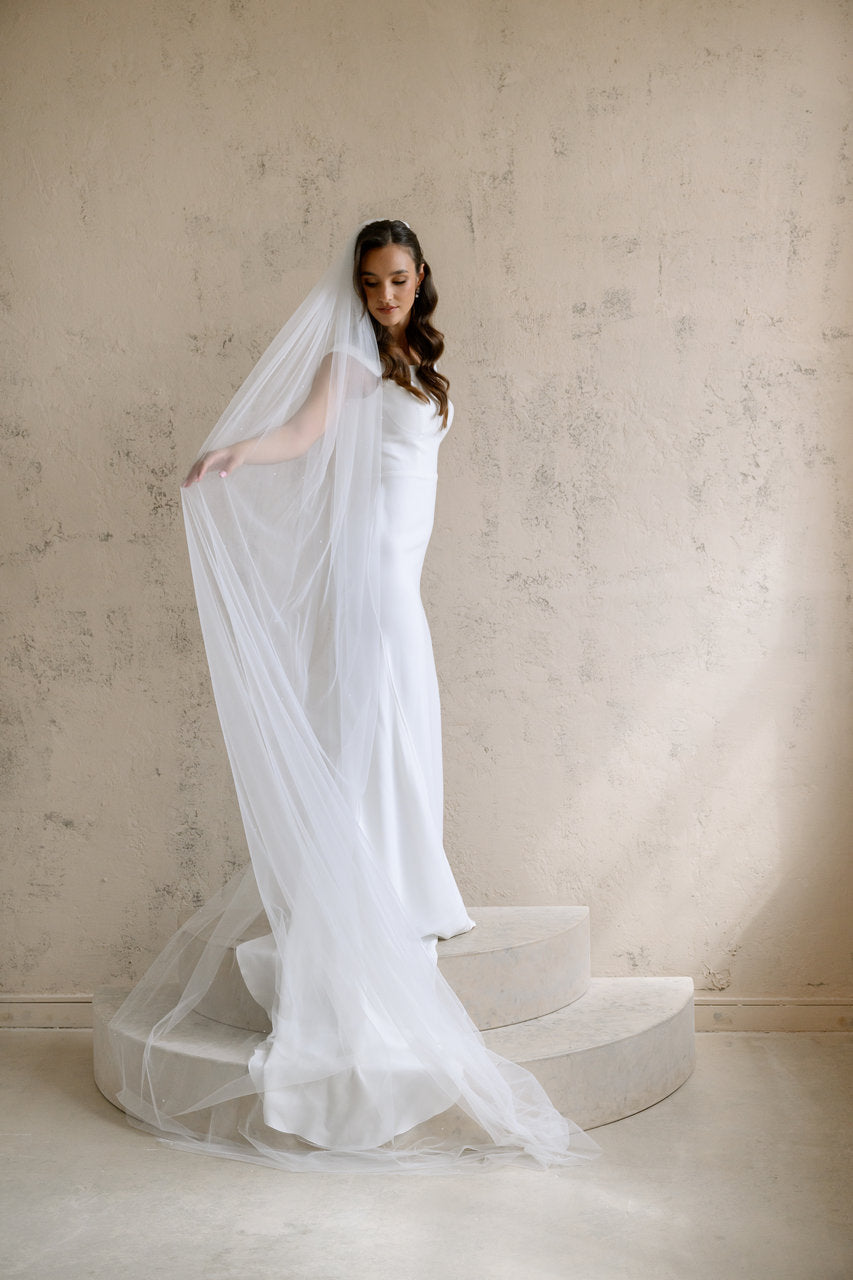 Voile de mariée Esmea 300 cm, demi-perles, tulle souple ivoire, vue de face avec voile déployé sur l'escalier