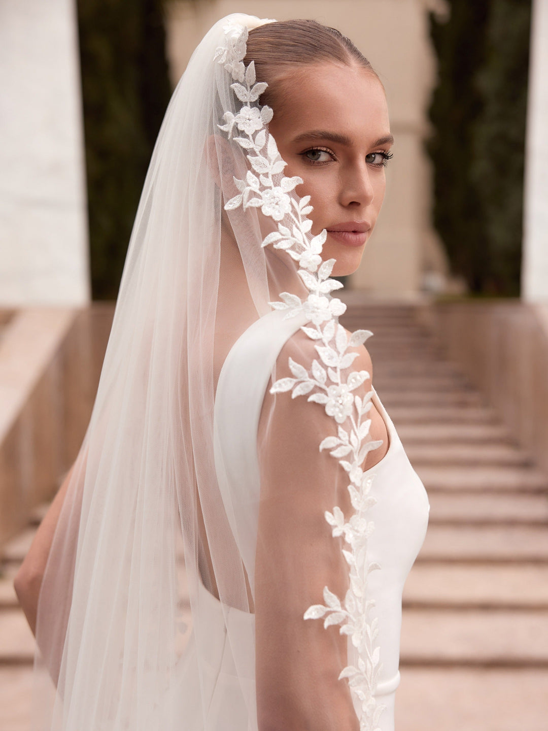 Détail des fleurs et feuilles de dentelle découpées sur un côté du voile de mariée S562 Bianco Evento
